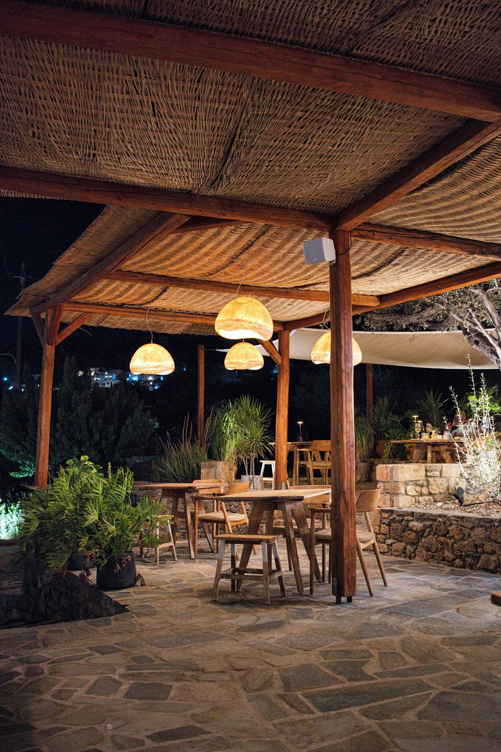 Cobertizo de madera iluminado sobre un patio con mesas